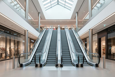 تصویری از چیدمان موازی پله برقی‌ها در یک فضای مدرن و پرتردد. پله برقی‌ها در کنار هم قرار گرفته‌اند و یکی در حال حرکت به سمت بالا و دیگری به سمت پایین است.