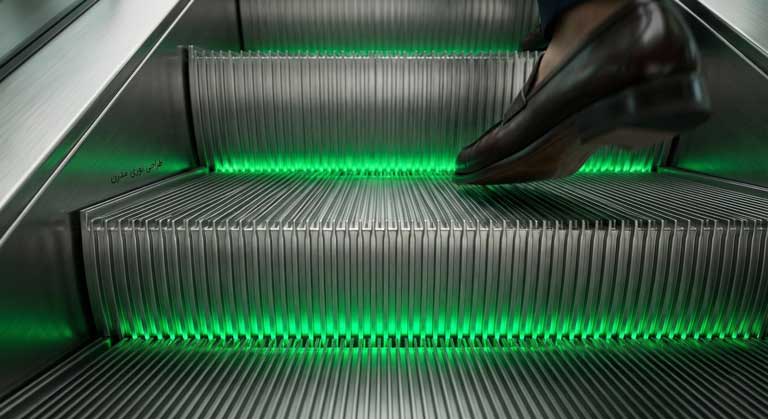 نورپردازی ایمنی و دکوراتیو سبز رنگ در زیر پله‌های پله برقی هتل.