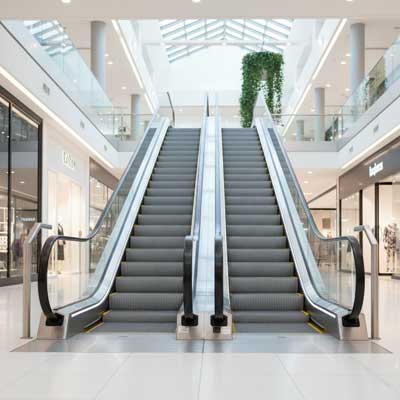 تصویری از یک پله برقی تجاری در محیطی داخلی و مدرن مانند مرکز خرید، با طراحی زیبا و شیشه‌ای.